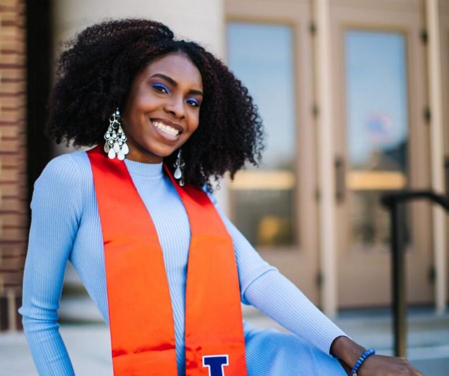 A student adorned in a graduation sash, beaming with a smile.