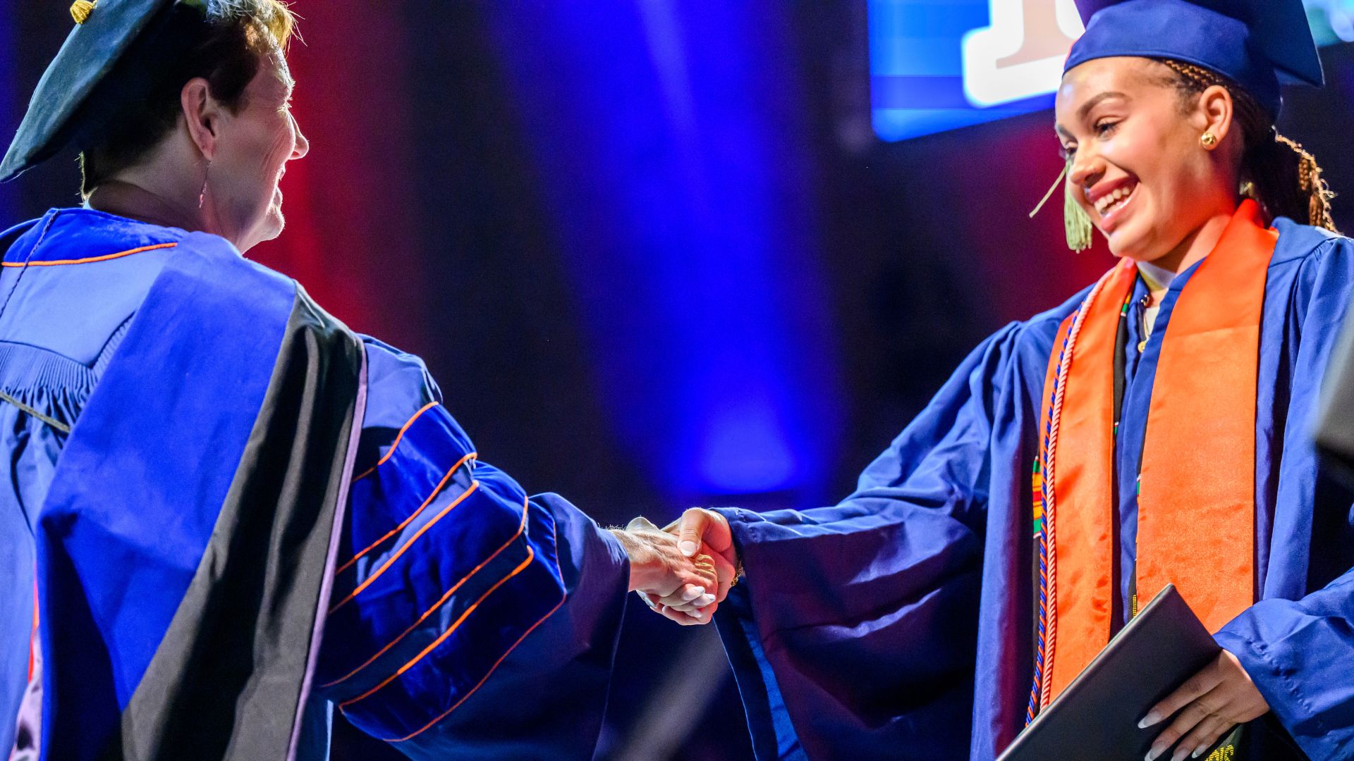 A graduate student and a professor exchanging a handshake.