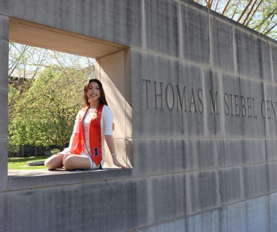 A cheerful student sits on a wall, with a sign indicating the Thomas M. Sibbel Centre nearby.